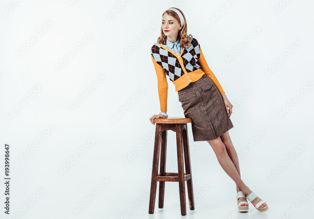 beautiful retro styled girl leaning on wooden chair on white