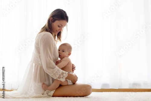 Slika na platnu Young mother breastfeeding her newborn baby boy at home