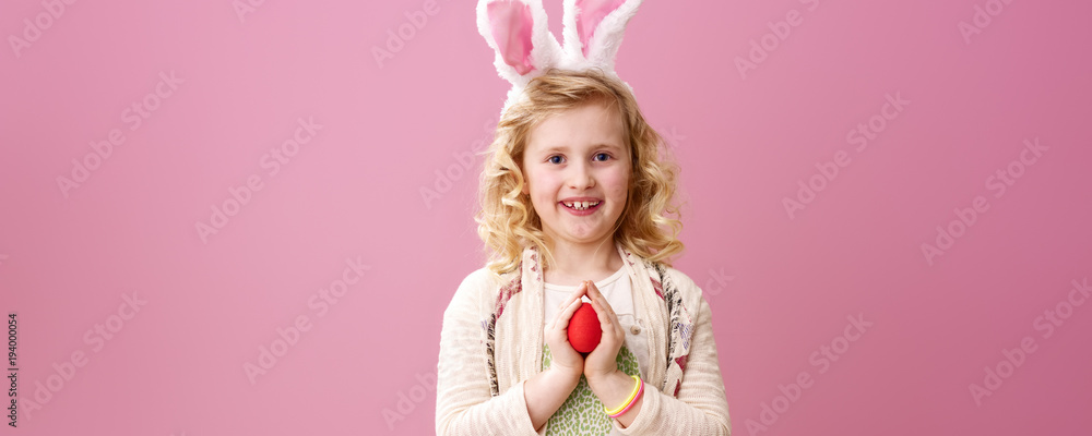 happy stylish child on pink background with red Easter egg