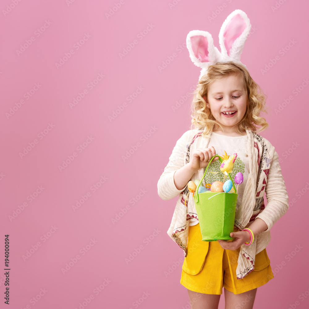 child on pink background looking at festive Easter eggs basket child on pink background looking at festive Easter eggs basket
