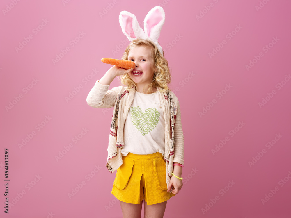 smiling child isolated on pink making long nose with carrot