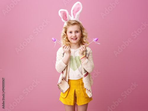 smiling girl isolated on pink with purple handmade Easter eggs