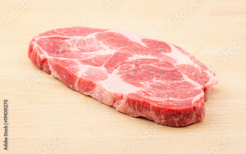 Raw pork neck meat cut isolated on wood background fresh one slice without bone .