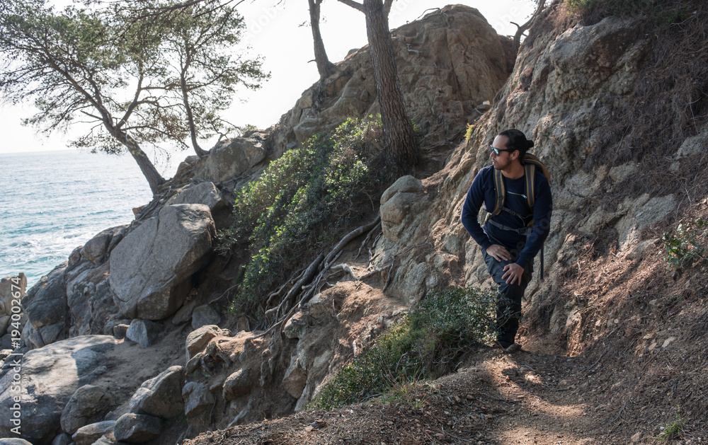Obraz premium man walking among the rocks near a beach paradise