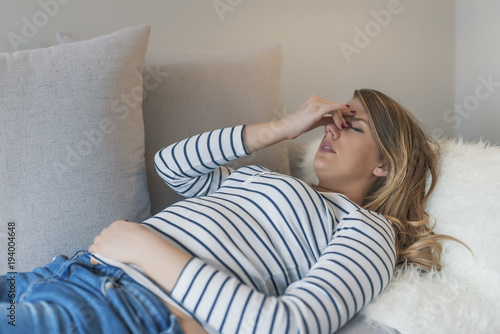 Woman with headache. Housewife woman in a couch with headache and a hand on forehead