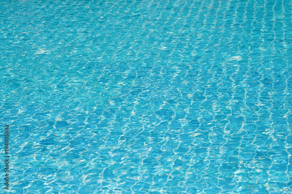 Blue and bright water surface and ripple wave with sun reflection in swimming pool