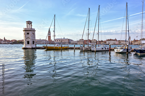 Daylight view to parked boats in a port with old stone tower