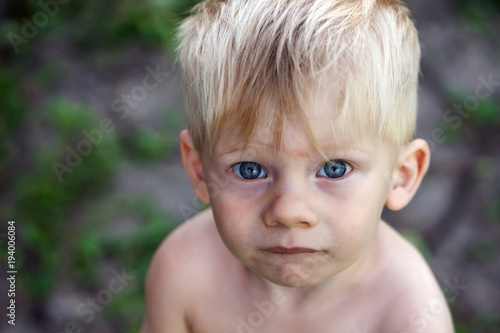 Portrait of a boy with blue eyes, a homeless child, a war child