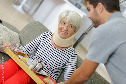 smiling old lady on sofa and nurse holding tray © auremar
