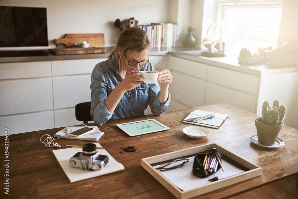 Young woman drinking coffee and working online from home