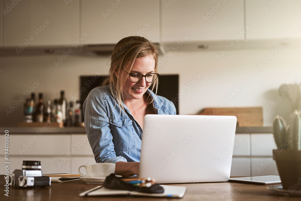 Smiling young female entrepreneur working online in her kitchen Smiling young female entrepreneur working online in her kitchen