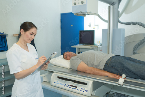 Patient on scanner bed  nurse making notes