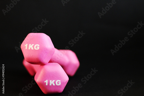 Isolated pink dumbbells, selective focus, black background, free copy space © Monika