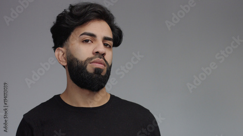 mixed eastern race man in studio in grey looking at camera