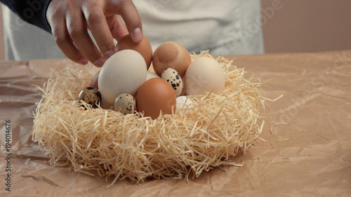 man takes eggs from the basket and put it to the baxoes. Small farmm worker photo