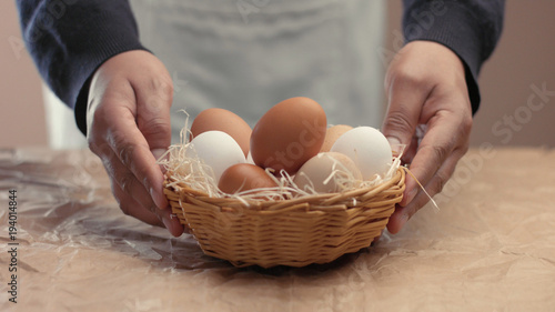 man takes eggs from the basket and put it to the baxoes. Small farmm worker photo