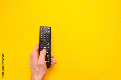 Fényképezés Television remote control in the hand isolated on yellow background
