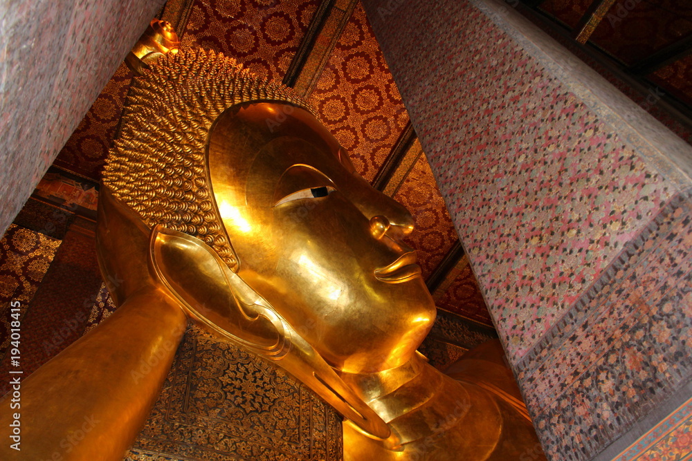 Head of Golden Reclining Buddha between columns in the temple Wat Pho, Bangkok Thailand