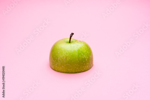 Half a green apple on pastel pink background. The concept of diet and weight loss.