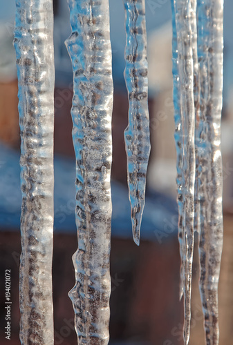 Bright transparent icicles against the background of the blue sky. Winter backdrop