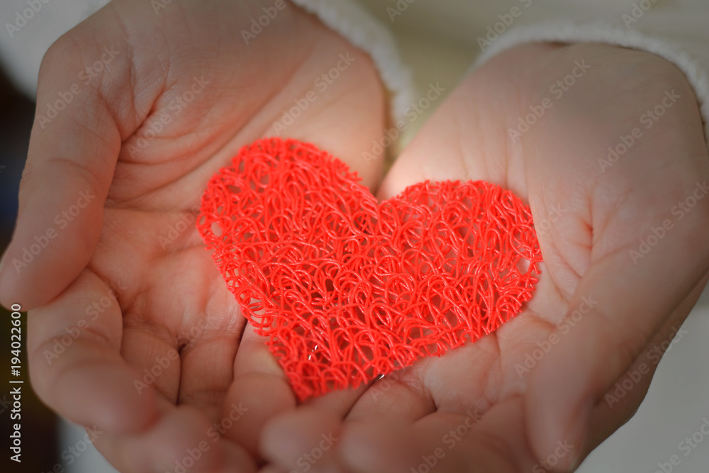 Obraz premium Decorative red heart in female hands. Valentine's Day. Love and romance. Medicine, health and care.