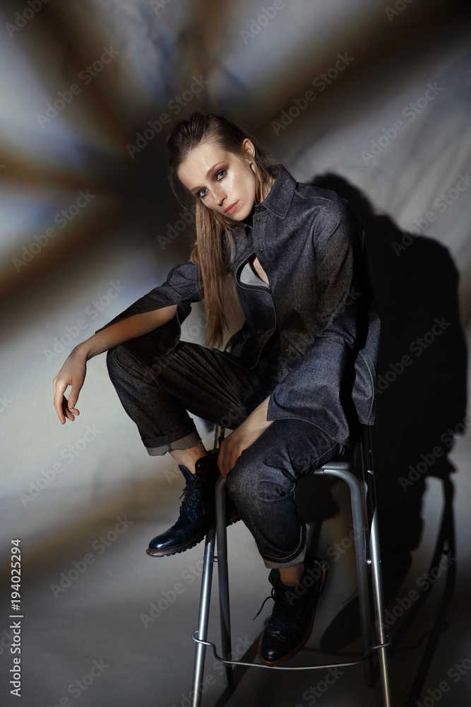 artistic portrait of a woman in a denim suit on a gray background