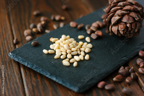 Pine nuts on black kitchen board over the wooden table.