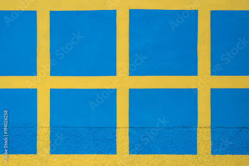Blue squares on a yellow stone wall, texture