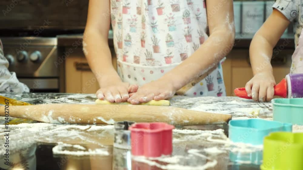 Charming girls are rolling dough using a rolling pin Charming girls are rolling dough using a rolling pin
