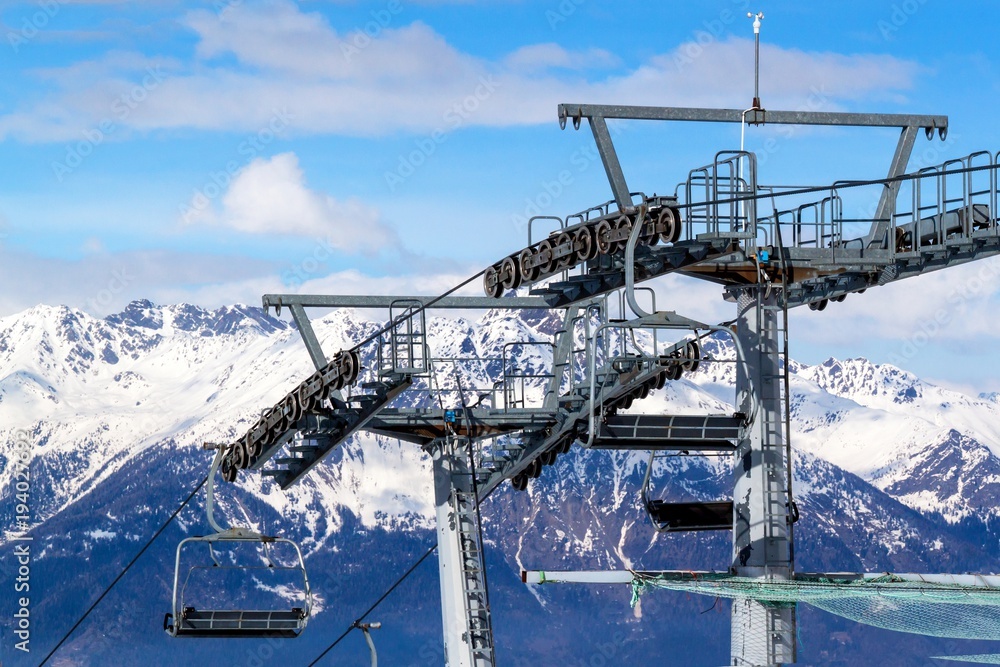 Fototapeta premium Chairlift in the Italian Alps. Chair lift in snowy mountains at nice sunny day.