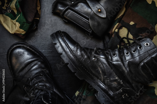 Army uniform military boots, boots, pants, bowler, pistol in holster on a dark background with copy space workspace flat lay top view © shintartanya