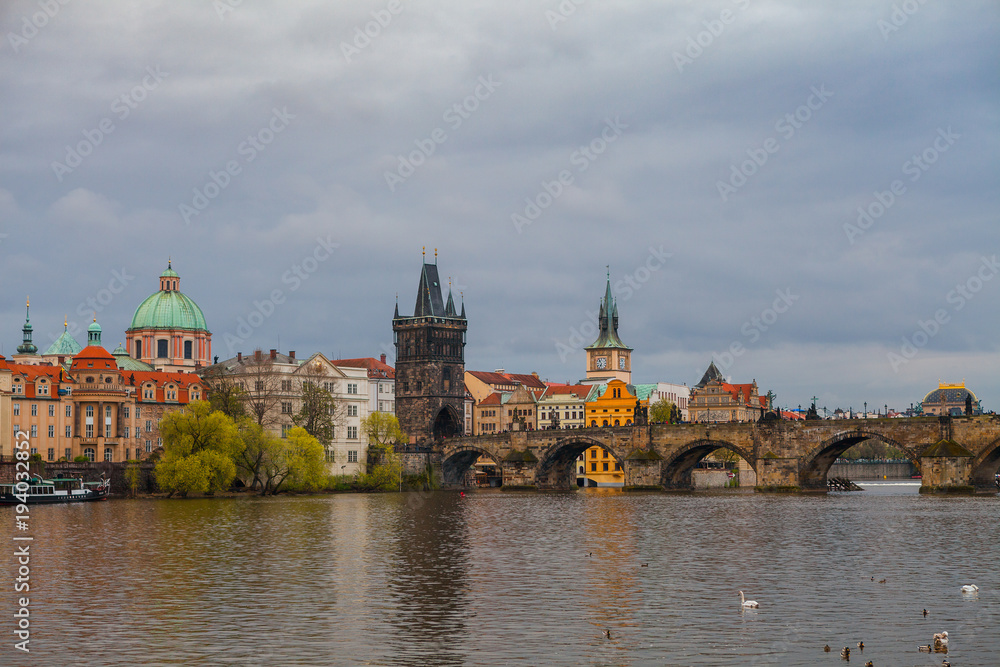 Charles bridge in gloomy day, Prague, Czech Republic. Water front of old museums.