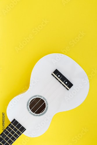 Musical concept. White Hawaiian guitar on a yellow background. Ukulele on a bright background