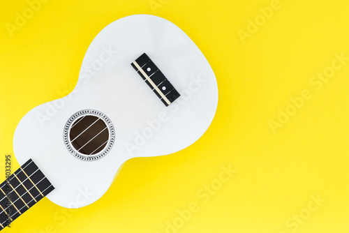 White ukulele on a yellow background. Flat lay Musical concept. Place for text.