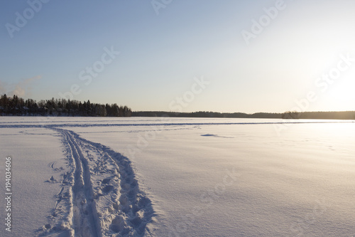 Wintry landscape from Finland. Deep snow with foot prints and ski trails.