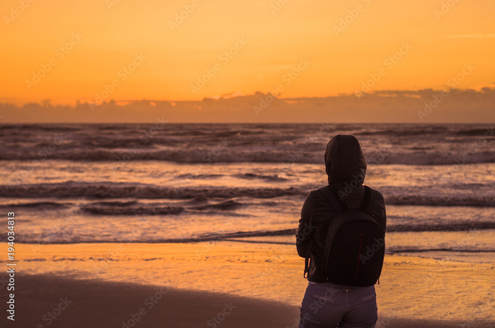 Woman looking at the horizon, beach at sunset