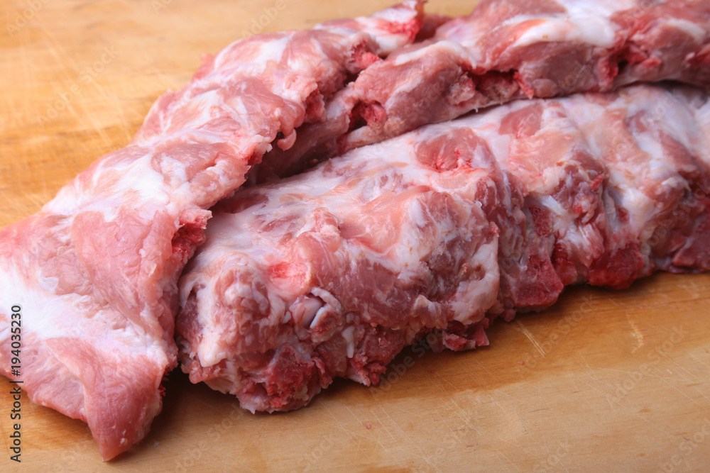 Raw Ribs on a rustic cutting board with salt, pepper and grinder for spices . copy space. Top View.