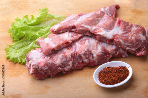 Raw Ribs on a rustic cutting board with salt, pepper and grinder for spices . copy space. Top View.