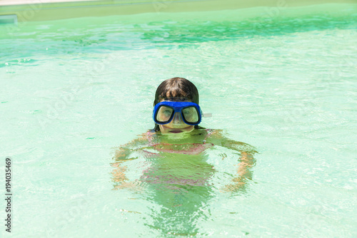 Little girl with diving glasses in an outdoor pool