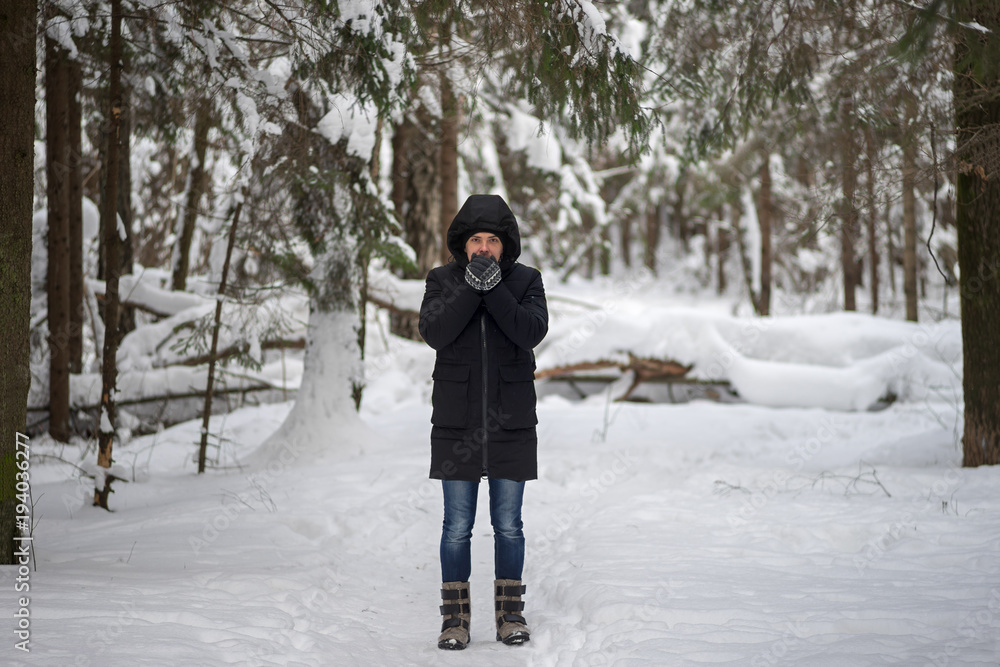 Man walk in snowy winter forest and warms your hands with your breath Man walk in snowy winter forest and warms your hands with your breath