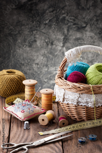 tangles of thread in a basket, scissors and threads in reels on a background of wooden boards