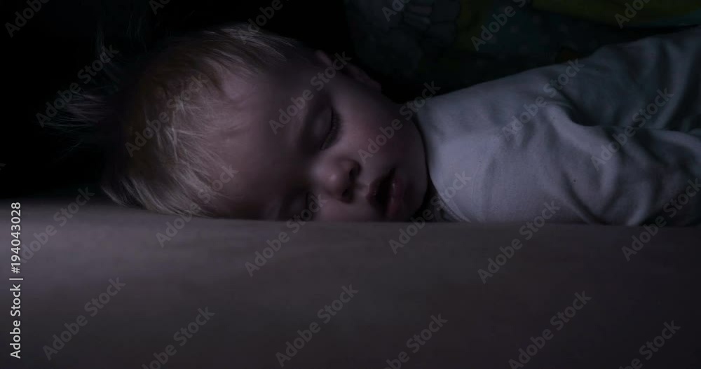 Little baby boy sweetly sleeps in bed, dad puts his son to bed. Little baby boy sweetly sleeps in bed, dad puts his son to bed.