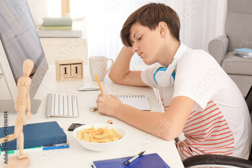 Cute teenager boy doing hom...