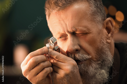 Jeweler evaluating gem with magnifier at workshop