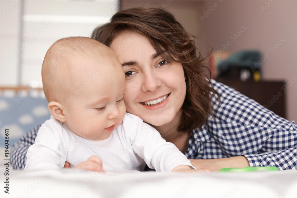 Young mother and her baby lying on bed at home Young mother and her baby lying on bed at home