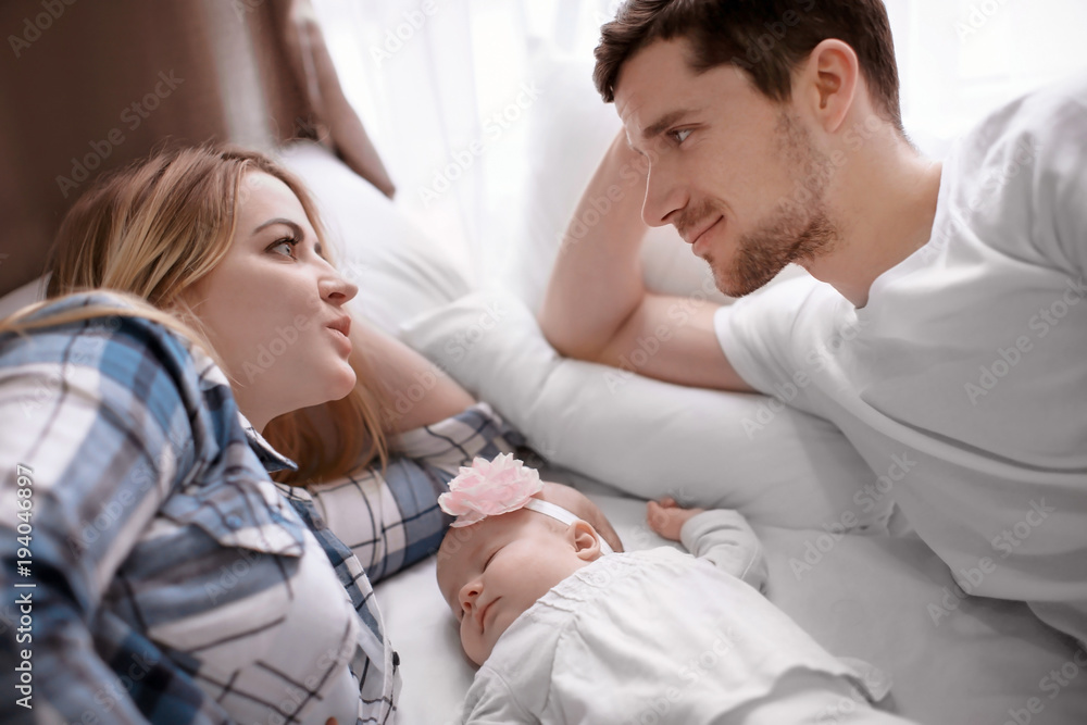 Fototapeta premium Young parents with cute sleeping baby on bed at home