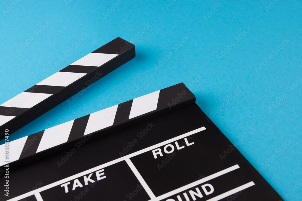 Movie clapper board on blue background with copy space, close-up, view from above. Cinema and movie time concept