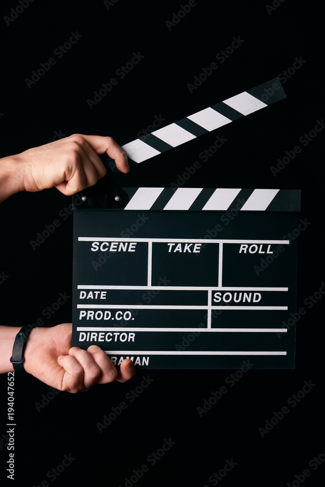 Hands with a movie clapperboard isolated on black background with copy space, close-up. Wooden clapper board as cinema and movie time concept