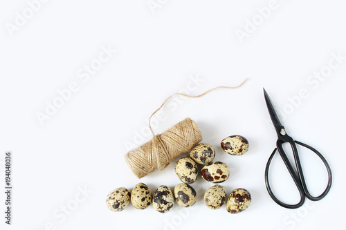 Easter, spring greeting card, invitation with quail eggs, black scissors and natural rope on white table. Feminine styled stock flat lay photo, top view.