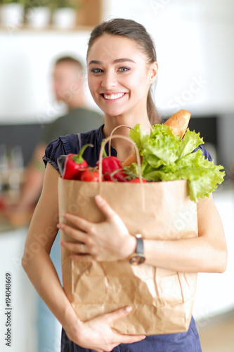 Young couple in the kitchen , woman with a bag of groceries shopping photo